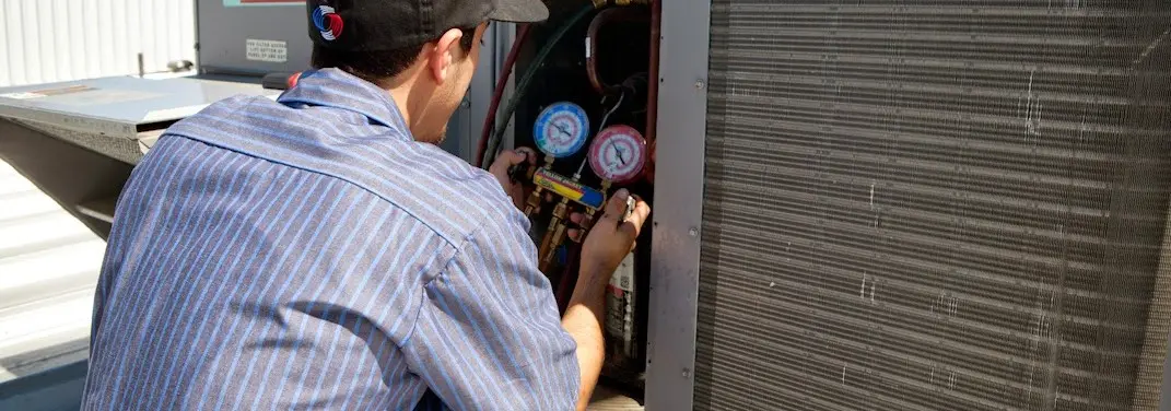 HVAC technician servicing a condenser unit in Highlands